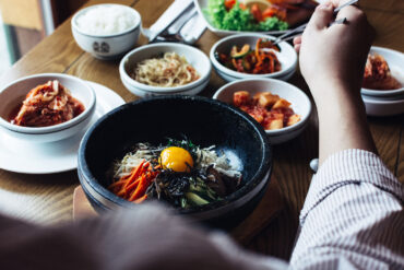 Korean bibimbap with egg yolk and assorted banchan on a dining table in Singapore