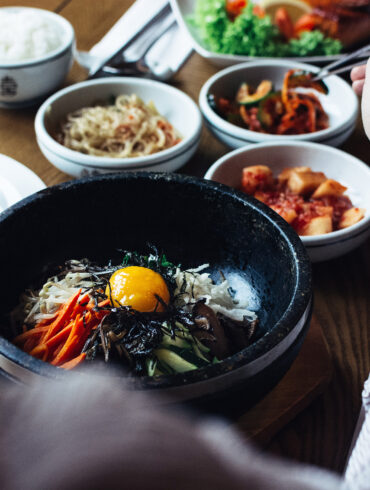 Korean bibimbap with egg yolk and assorted banchan on a dining table in Singapore