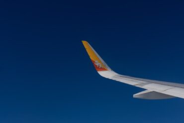Drukair aircraft wing with Bhutan’s dragon emblem flying against a clear blue sky
