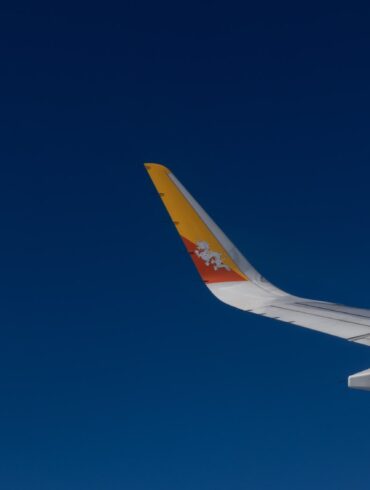 Drukair aircraft wing with Bhutan’s dragon emblem flying against a clear blue sky