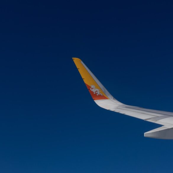 Drukair aircraft wing with Bhutan’s dragon emblem flying against a clear blue sky