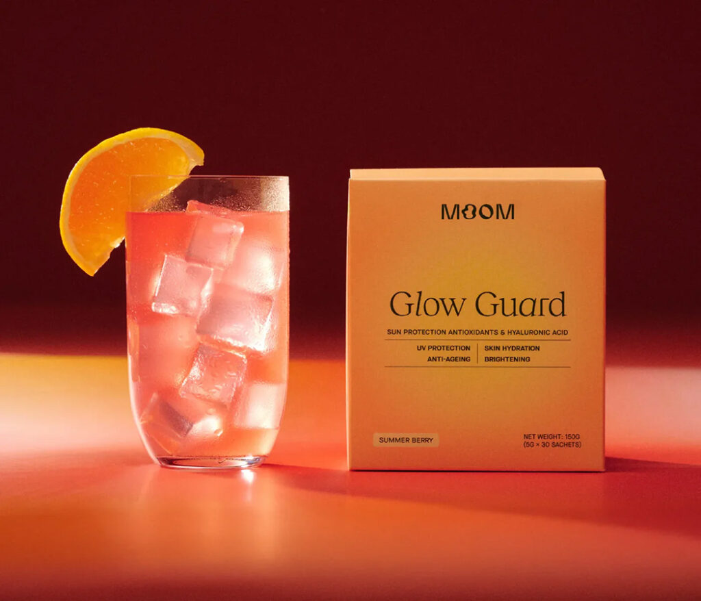 Moom Glow Guard supplement box in Summer Berry flavour next to an iced drink with an orange slice
