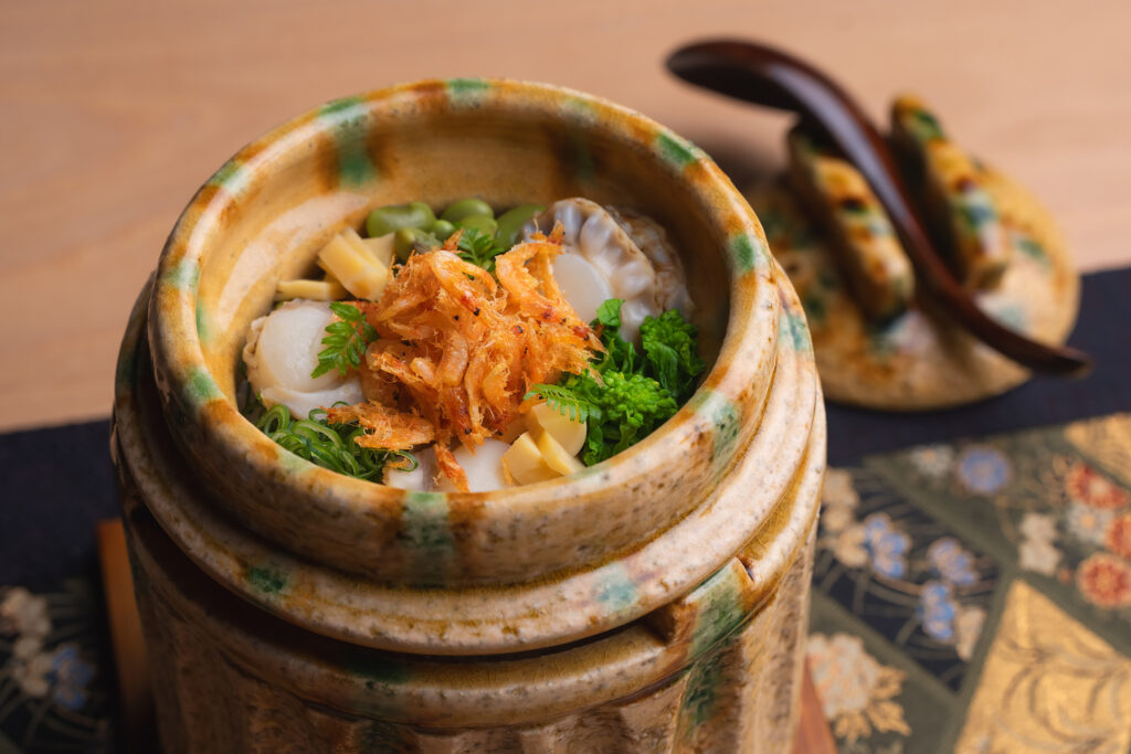 A handcrafted ceramic pot filled with sakura ebi rice, clams, edamame and spring greens, served at Hachi Restaurant's omakase in Singapore.