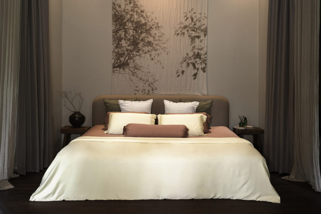 A neatly made bed dressed in Heveya bamboo lyocell sheets in warm neutral tones at the Heveya showroom in Singapore