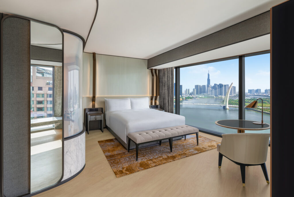 King bed with floor-to-ceiling Saigon River views in the Deluxe Corner Suite at Hilton Saigon, Ho Chi Minh City