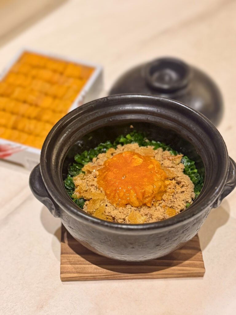 Close-up of Ichigo Ichie's Oyako Donabe — Japanese rice topped with chicken soboro and uni egg yolk sauce served in a black clay pot