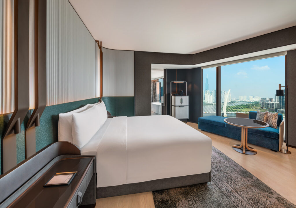 King Premium Corner Room bedroom with floor-to-ceiling windows and river view at Hilton Saigon