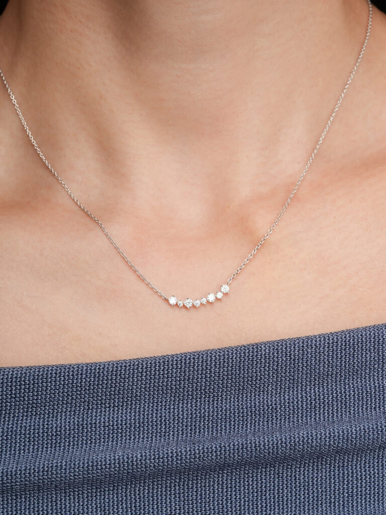Mondays Made Wishing Arc Moissanite Necklace worn on a model, featuring a delicate arc of moissanite stones on a silver chain