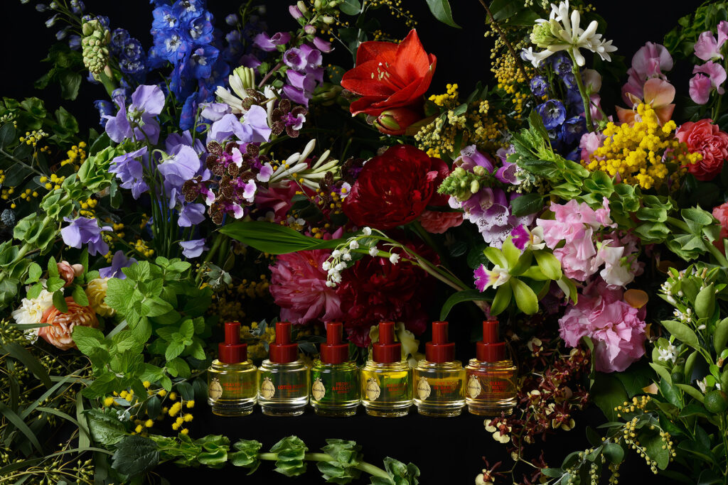 PAÑPURI Botanical Rhapsody perfume oil collection displayed against a dramatic backdrop of colourful botanicals