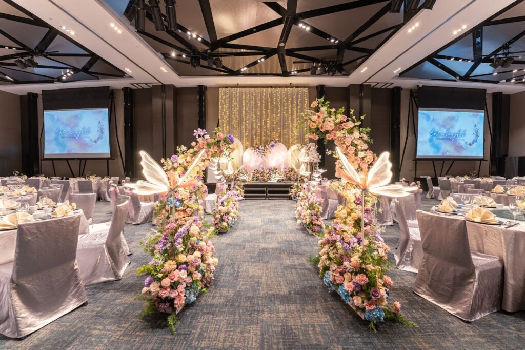 A decorated wedding banquet hall at Novotel Singapore on Stevens, with floral arches and butterfly sculptures lining the aisle