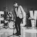Wedding live band performing on stage with singer and musicians in formal attire, entertaining guests at a reception with illuminated ‘LOVE’ letters.