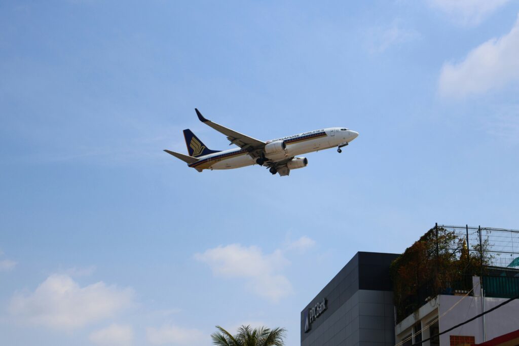 A Singapore Airlines passenger jet flying over an airport.