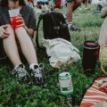 People sitting on grass at an outdoor festival enjoying drinks and food during a casual daytime gathering in Singapore