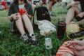 People sitting on grass at an outdoor festival enjoying drinks and food during a casual daytime gathering in Singapore