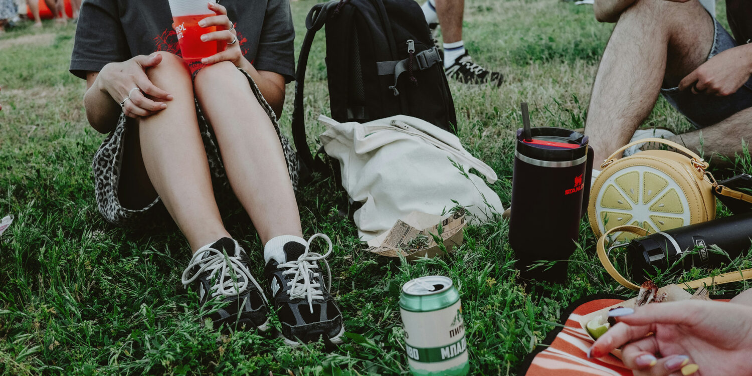 People sitting on grass at an outdoor festival enjoying drinks and food during a casual daytime gathering in Singapore