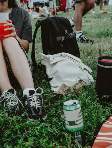 People sitting on grass at an outdoor festival enjoying drinks and food during a casual daytime gathering in Singapore
