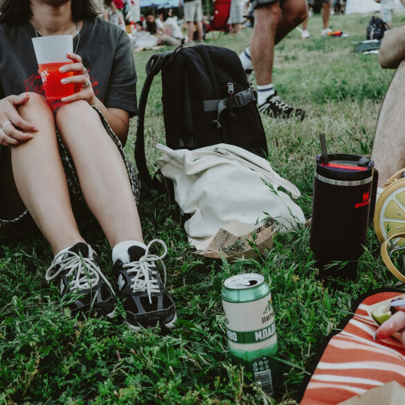 People sitting on grass at an outdoor festival enjoying drinks and food during a casual daytime gathering in Singapore