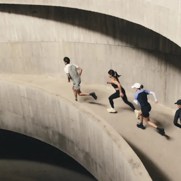 Four runners ascend a curved concrete ramp in a multi-storey car park, captured mid-stride from above during an On Squad Race event.