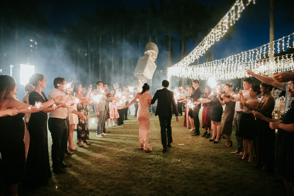 A couple walking through a sparkler exit at a night wedding on the W Lawn at W Singapore – Sentosa Cove