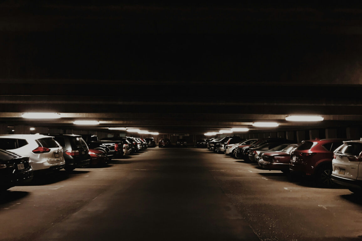 A dimly lit multi-storey carpark filled with cars at night