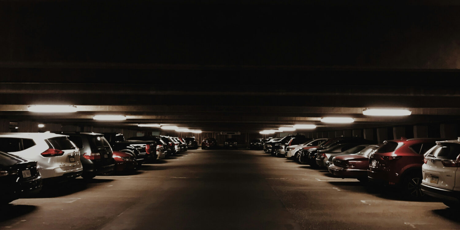 A dimly lit multi-storey carpark filled with cars at night