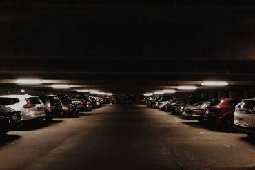 A dimly lit multi-storey carpark filled with cars at night