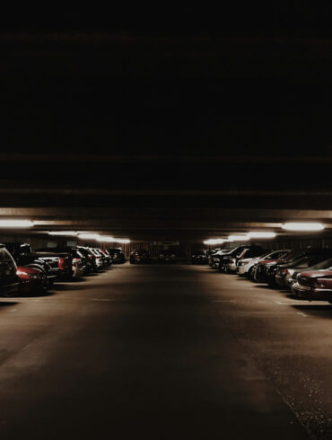 A dimly lit multi-storey carpark filled with cars at night