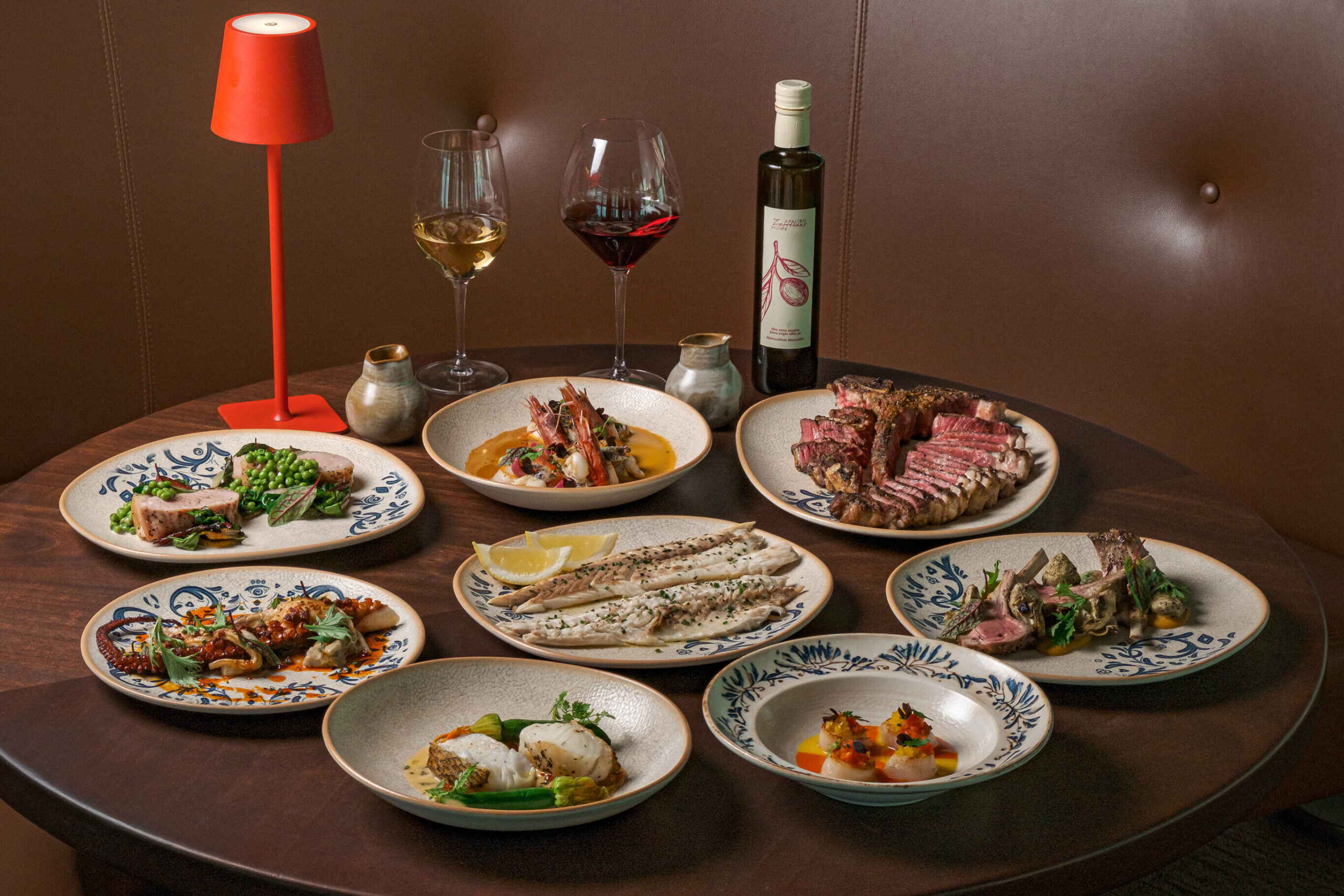 Italian set lunch spread at Altro Zafferano, Singapore, with multiple sharing plates of seafood, meat and fish dishes alongside wine and olive oil