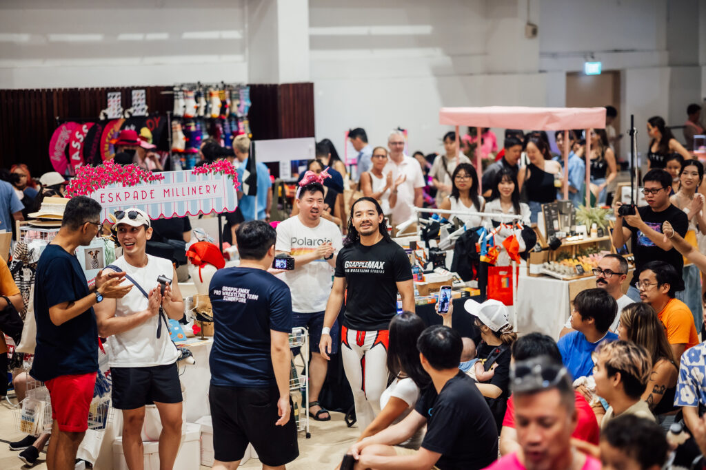 Crowd at Pasar Pink x Sunday Social at New Bahru, with GrappleMax wrestler walking through market stalls