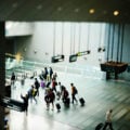 A group of travellers with luggage walks across the polished floor of a Changi Airport terminal, with directional signs to Terminal 3 and the Skytrain visible in the foreground.