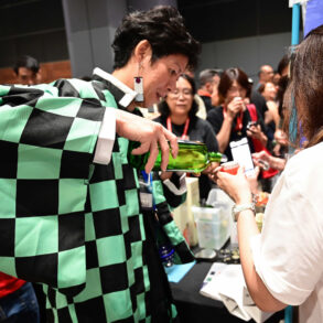 A sake brewer in a traditional Japanese haori jacket pours a sample for a visitor at Sake Festival Singapore.