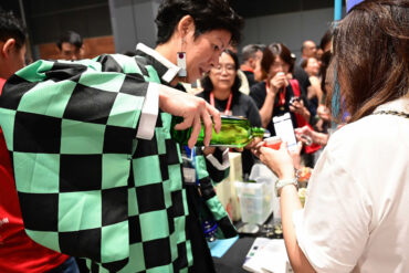 A sake brewer in a traditional Japanese haori jacket pours a sample for a visitor at Sake Festival Singapore.