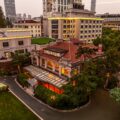 67 Pall Mall's Grand Mansion in Shanghai at dusk, with a red-tiled roof, glass conservatory and skyline backdrop.