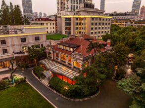 67 Pall Mall's Grand Mansion in Shanghai at dusk, with a red-tiled roof, glass conservatory and skyline backdrop.