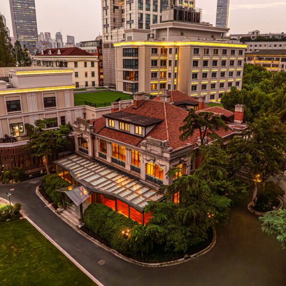67 Pall Mall's Grand Mansion in Shanghai at dusk, with a red-tiled roof, glass conservatory and skyline backdrop.