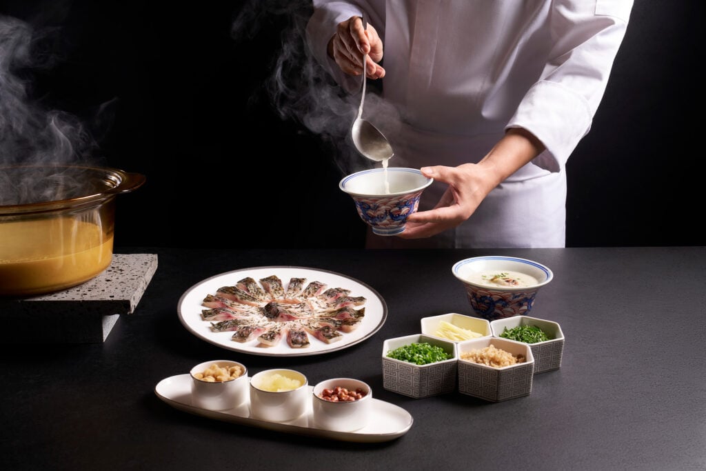 Chef ladling Boneless Crucian Carp Congee at Cherry Garden by Chef Fei, a Cantonese fine dining restaurant in Singapore