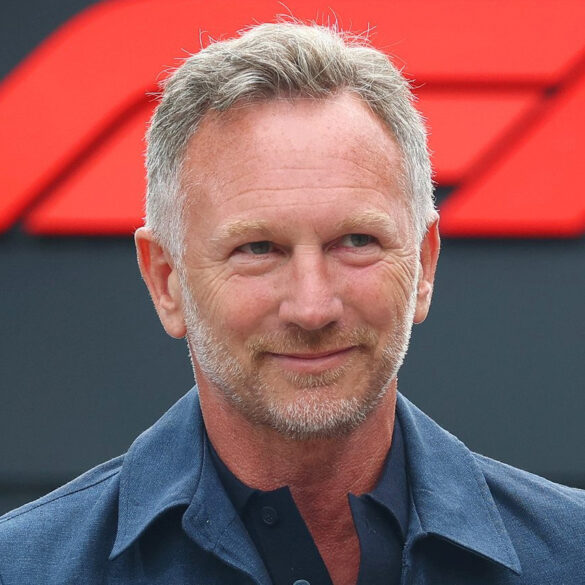 Christian Horner smiles in a navy shirt in front of an F1 logo backdrop, ahead of his Singapore live event Unfiltered