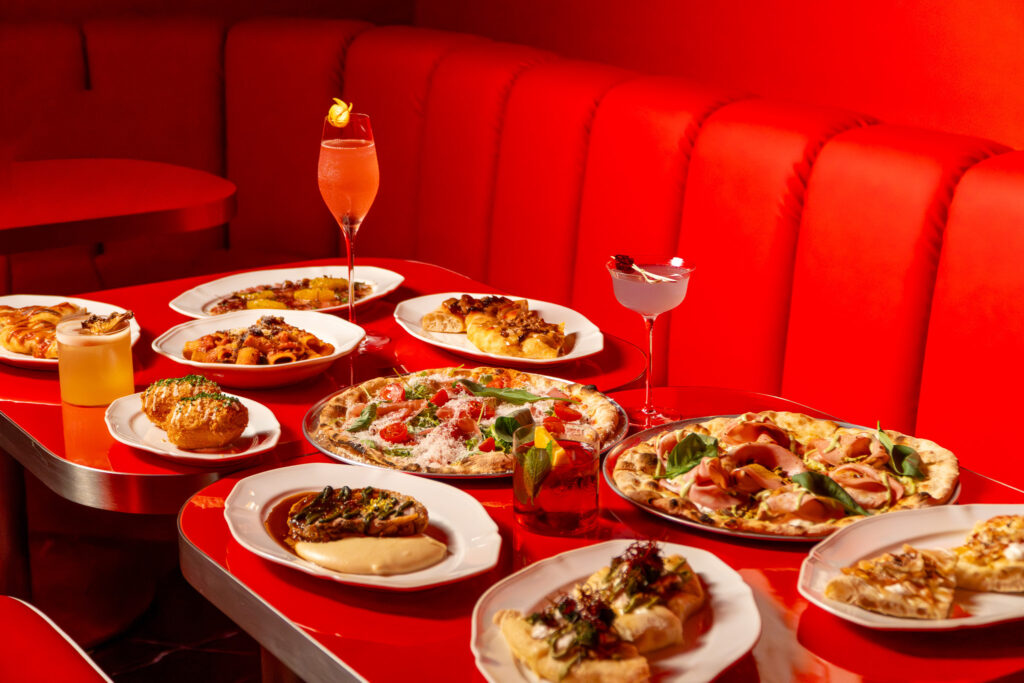 Pizza, pasta and cocktails on a red table at Medusa Italian Osteria Romana, a fine dining restaurant in Singapore
