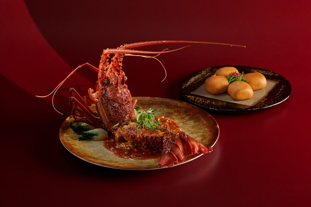 Singapore Chilli Half Rock Lobster with Golden Fried Mantou, plated whole with sauce, next to a side plate of fried mantou buns
