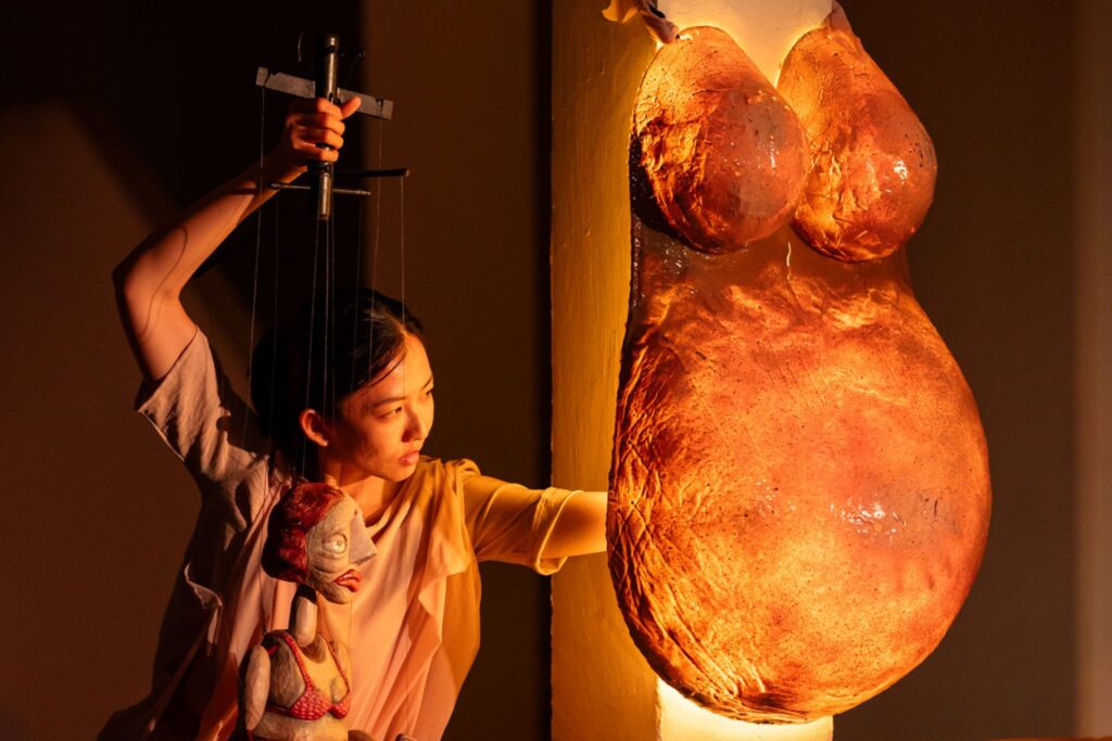 The Finger Players Singapore puppeteer operating a marionette alongside a large sculptural prop on stage