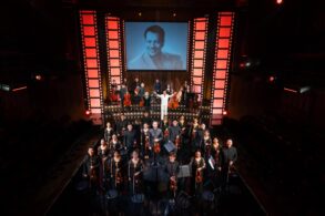 re:mix chamber orchestra and cast take a bow on stage at Wild Rice's Tunggu Sekejap: The P. Ramlee Suite, with a portrait of P. Ramlee projected behind them