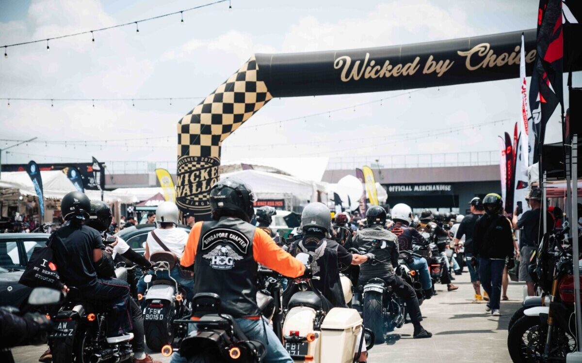 Motorcyclists ride under the checkered Wicked by Choice arch at Wicked Wallop Drop in Singapore.