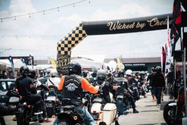 Motorcyclists ride under the checkered Wicked by Choice arch at Wicked Wallop Drop in Singapore.
