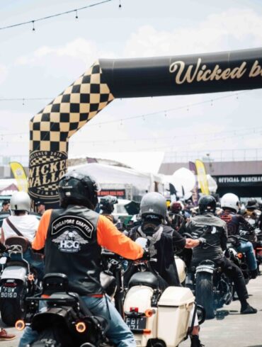 Motorcyclists ride under the checkered Wicked by Choice arch at Wicked Wallop Drop in Singapore.