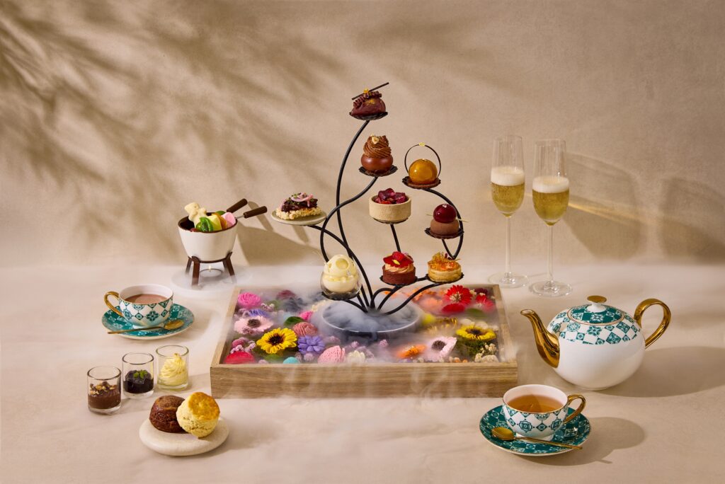 A tiered stand of chocolate pastries and savoury bites on a floral display tray, served with champagne and tea at The Lobby Lounge, Frasers House.