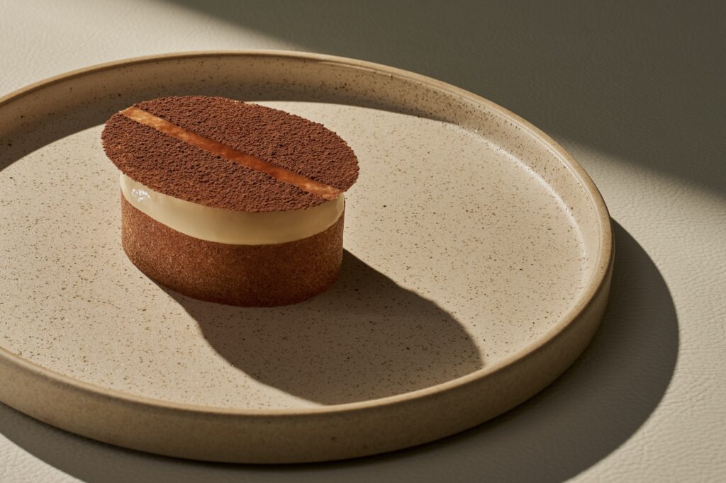 A round tiramisu dessert topped with a cocoa-dusted tuile, plated at LOULOUCA.