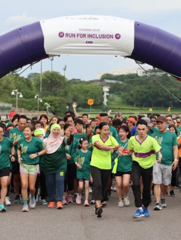 Runners of all abilities crossing the start arch at Runninghour's Run For Inclusion, cheering as they set off from Bedok Reservoir