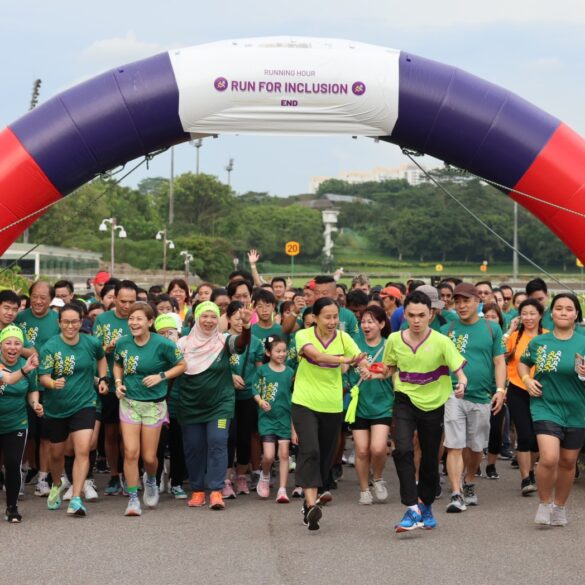 Runners of all abilities crossing the start arch at Runninghour's Run For Inclusion, cheering as they set off from Bedok Reservoir