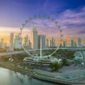 Aerial view of the Singapore Flyer and Marina Bay skyline at sunrise, with the Marina Bay Street Circuit track visible below