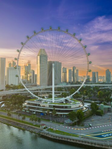 Aerial view of the Singapore Flyer and Marina Bay skyline at sunrise, with the Marina Bay Street Circuit track visible below